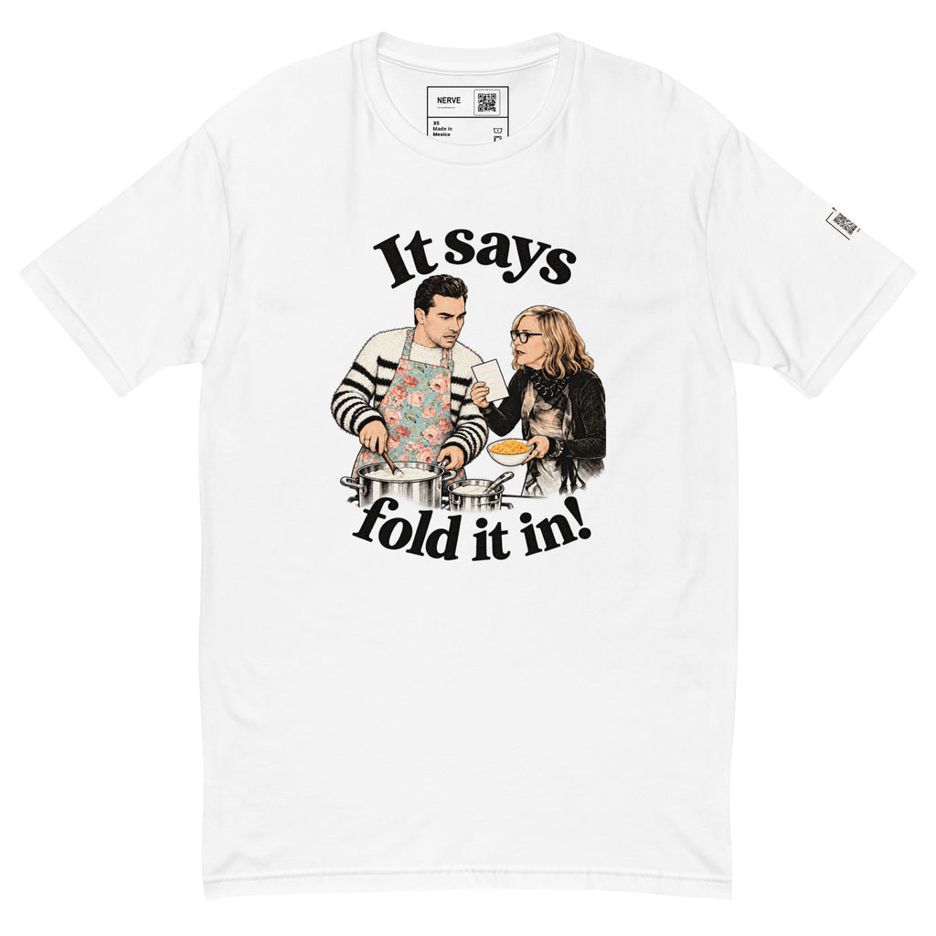 White short-sleeve tee with “It says fold it in!” lettering, a man stirring a pot and a woman holding a card and bowl.