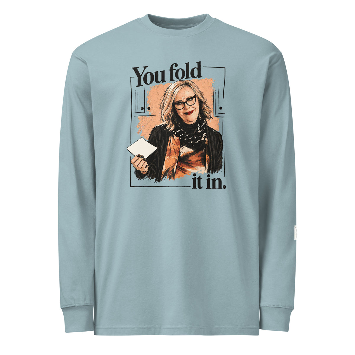 Agave long-sleeve tee with “You fold it in.” lettering and a woman in glasses holding a card.