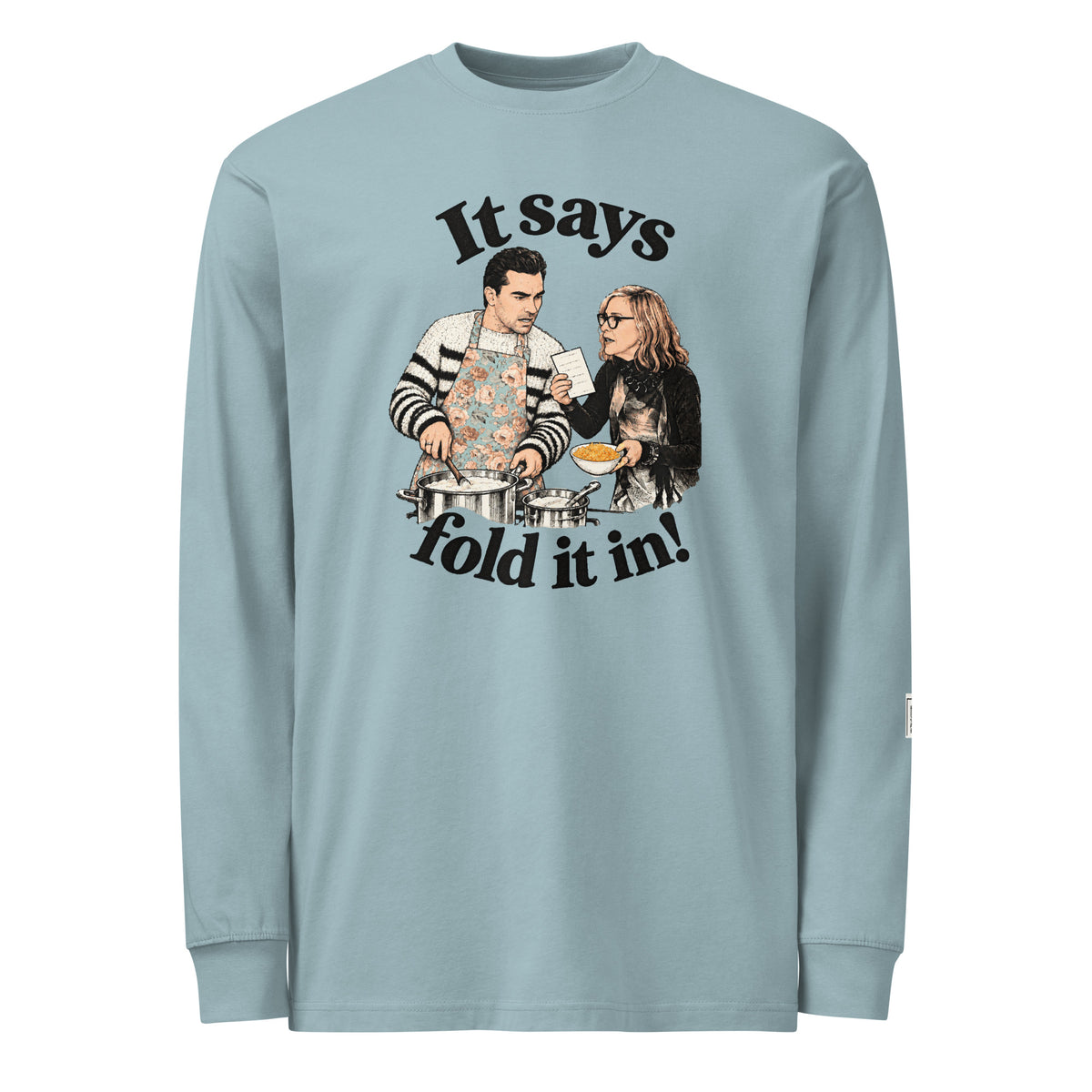 Agave long-sleeve tee with “It says fold it in!” lettering, a man in an apron stirring a pot and a woman holding a card and bowl.